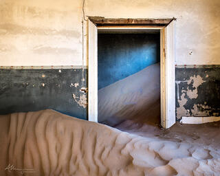 An abandoned furnished building in Kolmanskop, reclaimed but the shifting sands of the desert.