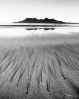 The view of the Island of Rum, Scotland, seen from Laig beach on Eigg with interesting sand patterns on the beach.