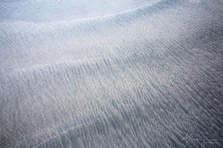The darker and lighter sand give the impression of undulations on the coastline.