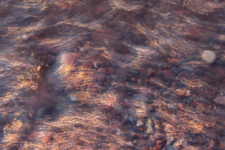 waves washing over pebbles at sunset