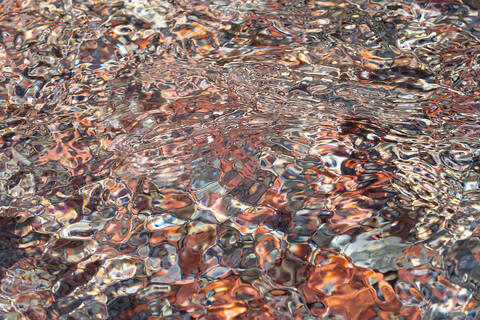 water moving over multicoloured bright rocks distorting the rocks and patterns.