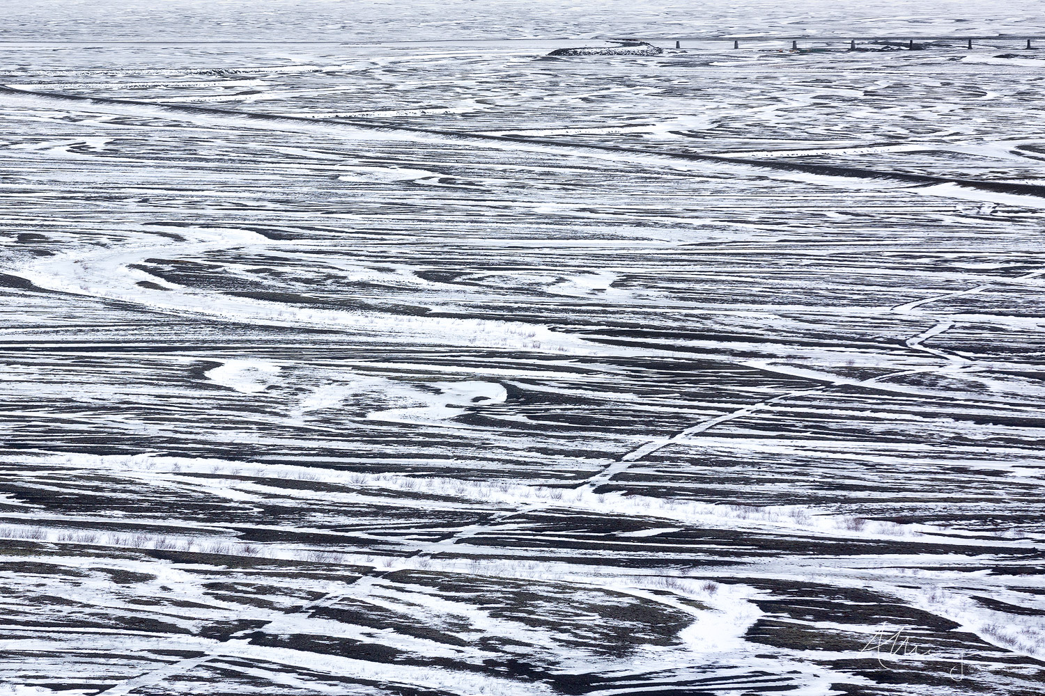 Remains A view of the patterns of a snow covered glacial outwash plain in Southern Iceland with the remains of Skeiðará bridge in the distance.